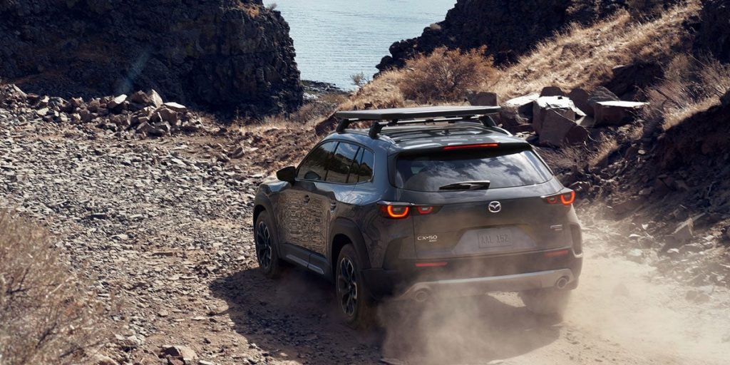 2024 Mazda cx50 driving down dirt road along a lake